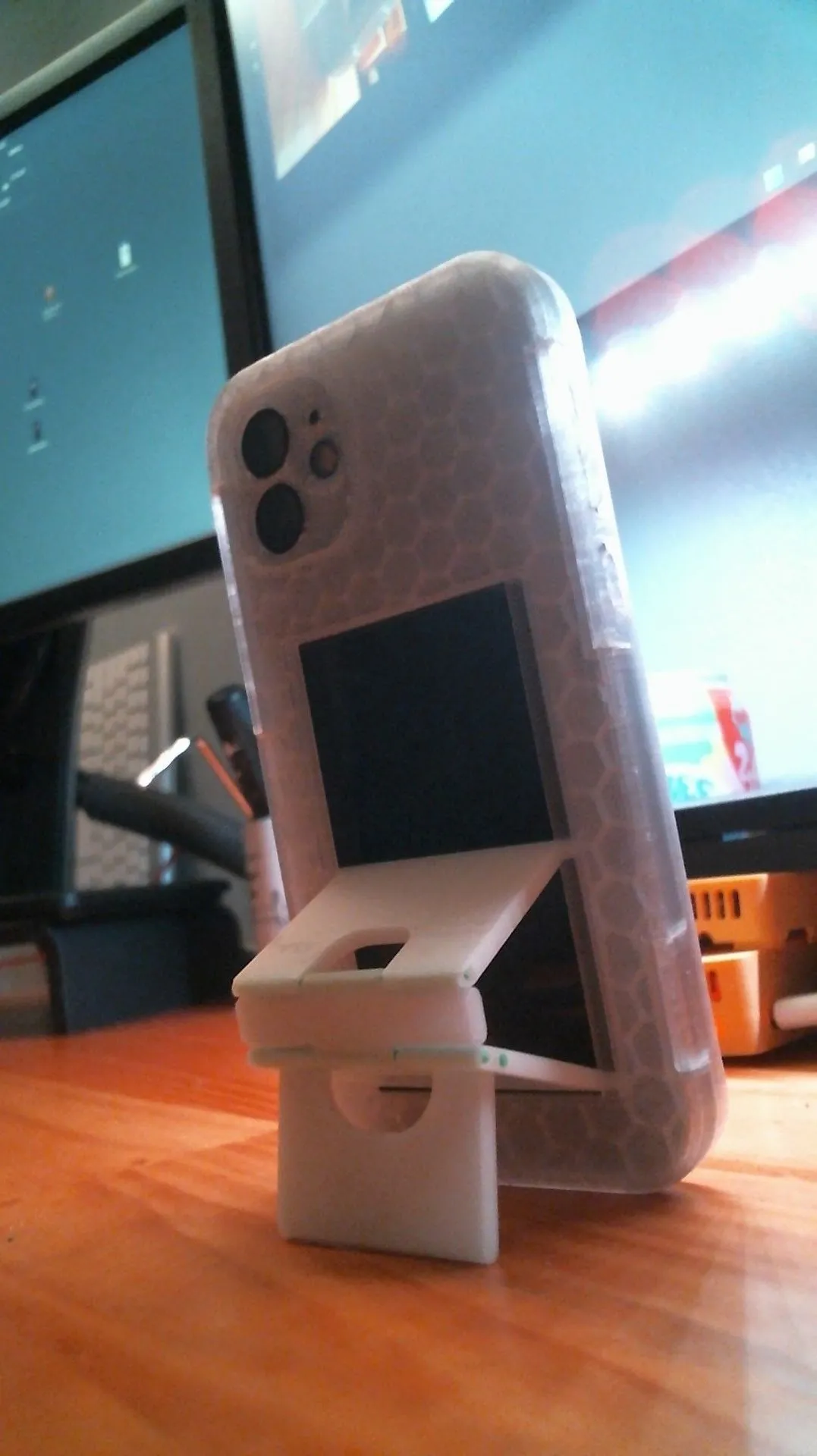 Folding phone kickstand case standing upright in front of a monitor